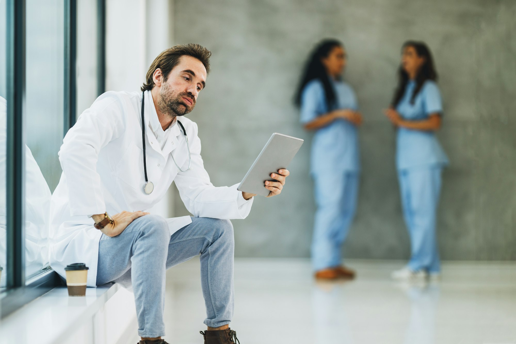 A Worried Doctor Using Digital Tablet In A Hospital Hallway